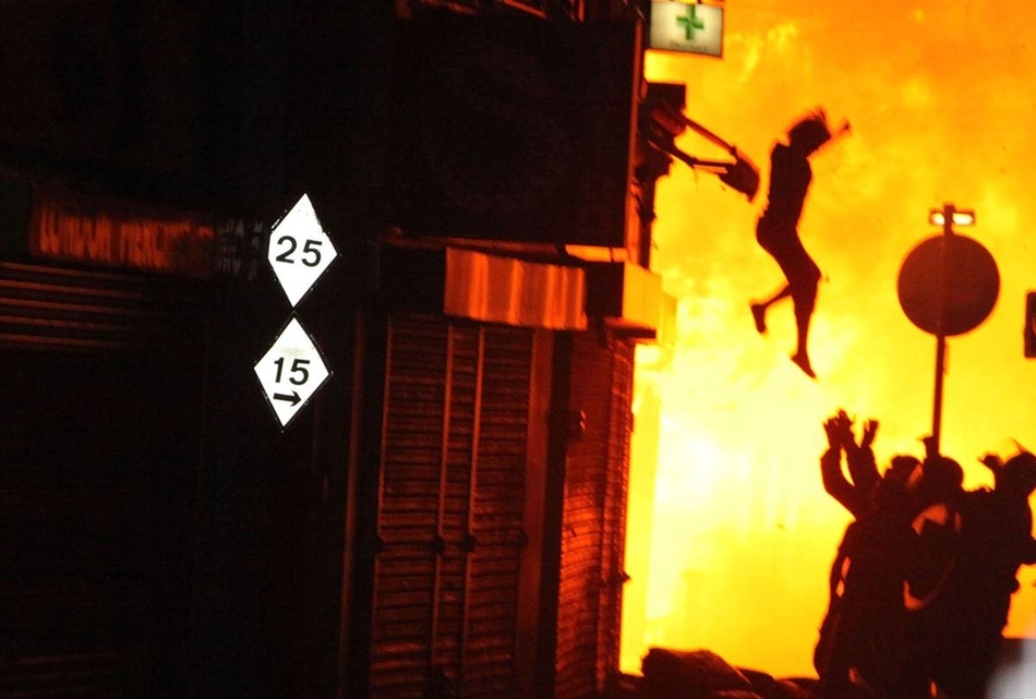 Γυναίκα πηδάει από ένα κτίριο που καίγεται κατά τη διάρκεια των ταραχών του Λονδίνου τον Αύγουστο