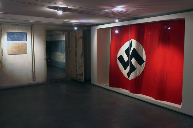 Η ναζιστική σημαία που κυμάτιζε στο κτίριο, και μία πόρτα από το κολαστήριο της Γκεστάπο στην οδό Μέρλιν. Μάριος Βαλασόπουλος
