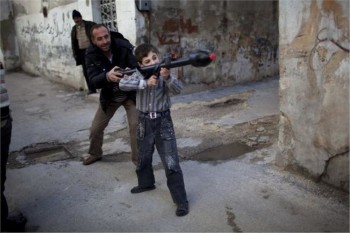 Ανδρας μαθαίνει τα «μυστικά» του πολέμου και των όπλων στον 11χρονο Μπιλάλ στη βόρεια Συρία.Από τη σειρά φωτογραφιών του ΑΡ που κέρδισαν τον διαγωνισμό Πούλιτζερ. (AP Photo/Rodrigo Abd, File) 