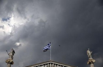 A Greek national flag flutters next to statues of ancient Goddess Athena and God Apollo atop the Athens Academy
